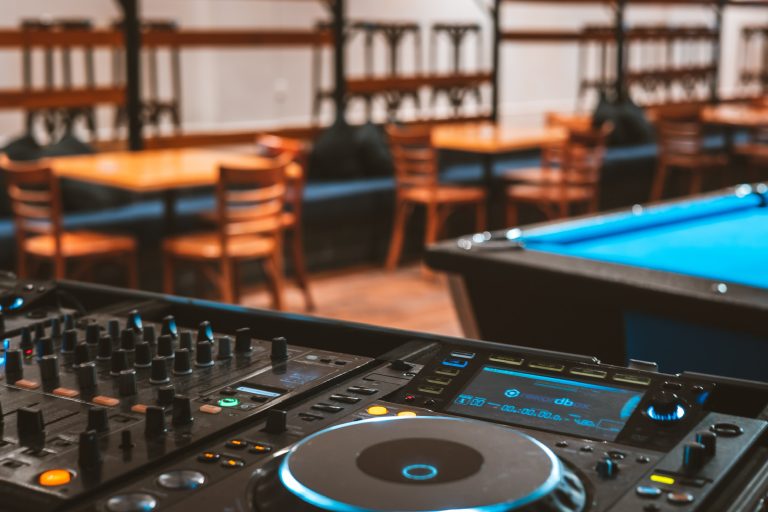 DJ equipment set up in a function venue in Richmond with tables and seating in the background.