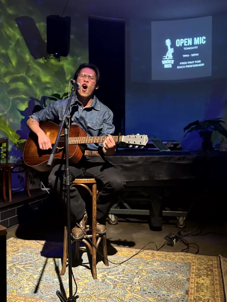 Musician performing on stage with guitar at Open Mic Night in Richmond.